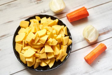 Tahtada dilimlenmiş çiğ patates. Pişirmek için sebze hazırlıyorum..