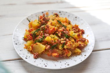 Hafif ahşap zemin üzerinde fırında patates, kıyma, soğan ve havuç..