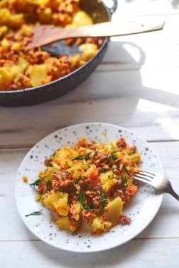 Hafif ahşap zemin üzerinde fırında patates, kıyma, soğan ve havuç..