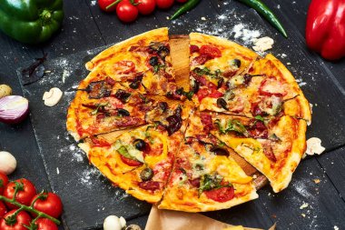 Mozzarella peynirli pizza, domates, mantar, biber, siyah ahşap arka planda otlar..