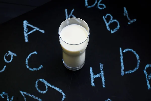우유에 비타민의 액체가 유리잔 과검은 바탕에 비타민이라는 이름이 유리잔 — 스톡 사진