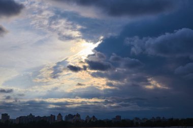 Nehrin ve şehrin üzerindeki kara bulutların arasından güneş ışınları süzülüyor..