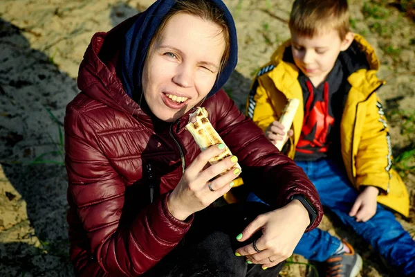 Mom and son eat at a picnic.