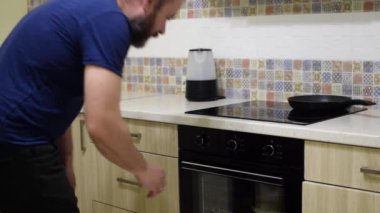 Adam mutfaktaki fırını açıyor. Bir adam turta hazırlıyor..