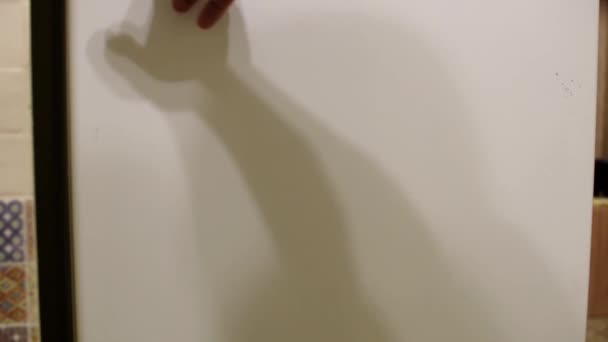 Un homme dépose une bouteille de vin dans un réfrigérateur vide. Le concept d'alcoolisme, de dégradation, de pauvreté .