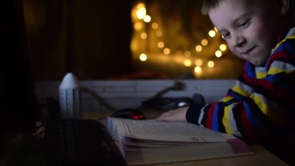 Niño Está Leyendo Libro Delante Una Computadora Distraído — Vídeo de stock