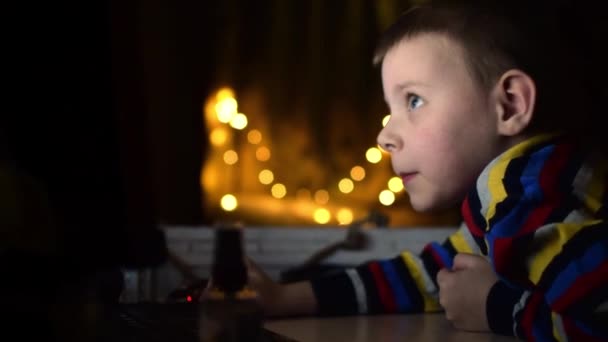 男の子がキーボードを押している 子供はふける暗い部屋のコンピューターで遊ぶ — ストック動画
