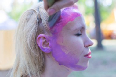 Peri masalı karakterine bürünmüş bir kadının yüzü. Yüze pembe bir su rengi uygulamak.