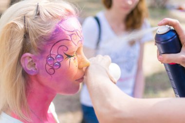 Peri masalı karakterine bürünmüş bir kadının yüzü. Yüze pembe bir su rengi uygulamak.