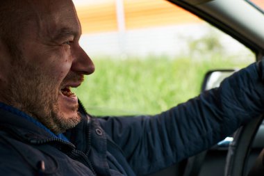 Bir adam araba sürerken gülümser. Şeytani gülümseme.