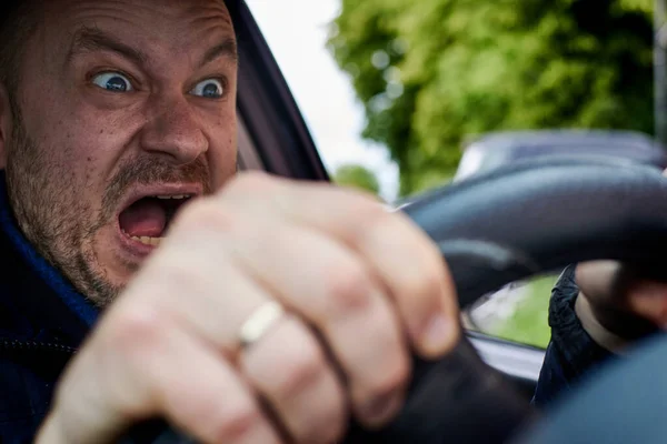 A man screams at the wheel of a car. Shocked driver. A scream of fear of a traffic accident.