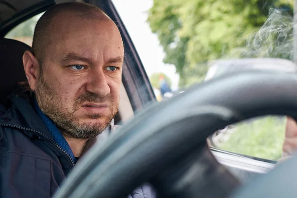 Bir adam direksiyonda sigara içer..