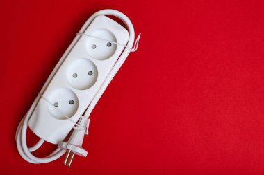 Kırmızı arka planda elektrik uzatma kablosu. Elektriklendirme kavramı.
