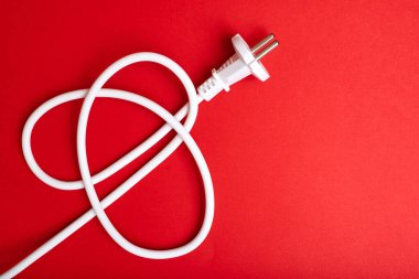 Kırmızı arka planda kablosu olan elektrik prizi. Elektrik, elektrik kavramı.