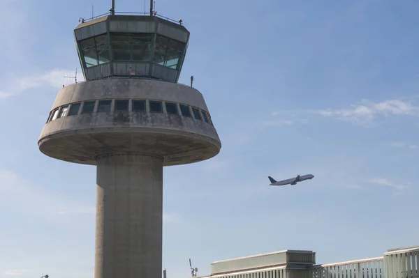 Um avião voa ao lado da torre de controle no Aeroporto de Barcelona, Sp — Fotografia de Stock