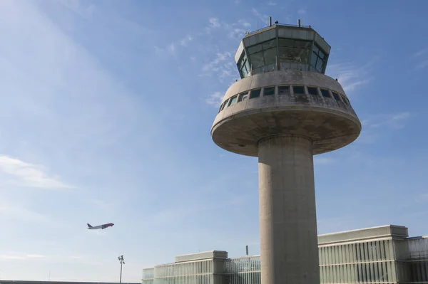 Un avion vole à côté de la tour de contrôle à l'aéroport de Barcelone, Sp — Photo