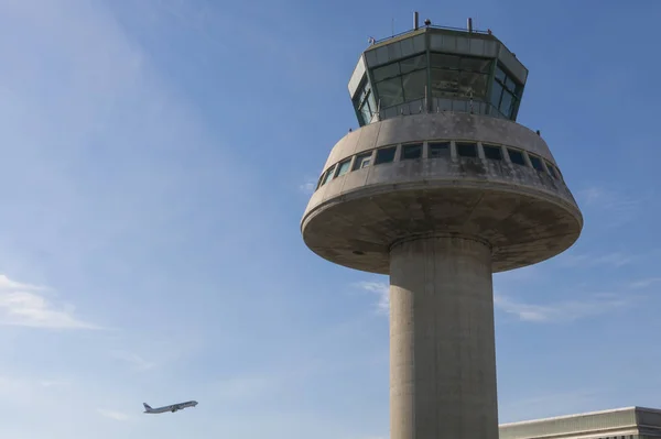 Un avión vuela junto a la torre de control en el aeropuerto de Barcelona, Sp — Foto de Stock