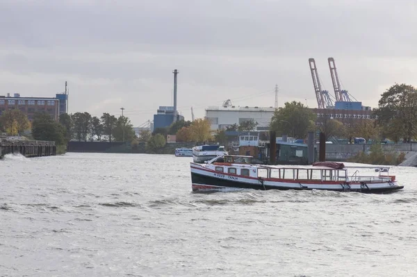 Båt går floden Elbe i Hamburg med frakttrafiken i backgro — Stockfoto