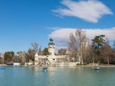 Beautiful picture of tourists on boats at pond of the Parque del Buen Retiro - Park of the Pleasant Retreat in Madrid, Spain clipart