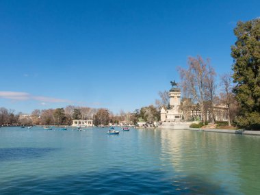 Beautiful picture of tourists on boats at pond of the Parque del Buen Retiro - Park of the Pleasant Retreat in Madrid, Spain clipart