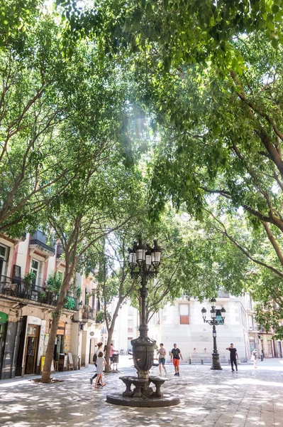 Изображение окаймленной деревьями площади Сан-Агусти Велл, в центре — стоковое фото