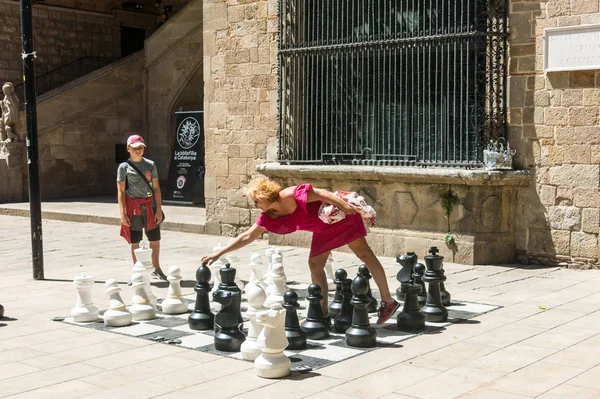 A mother and her son play with a giant chess in the square of th — Stock Photo, Image