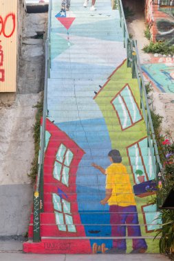 Rengarenk duvar yazısının altında elinde bir kişi olan merdivenler. 
