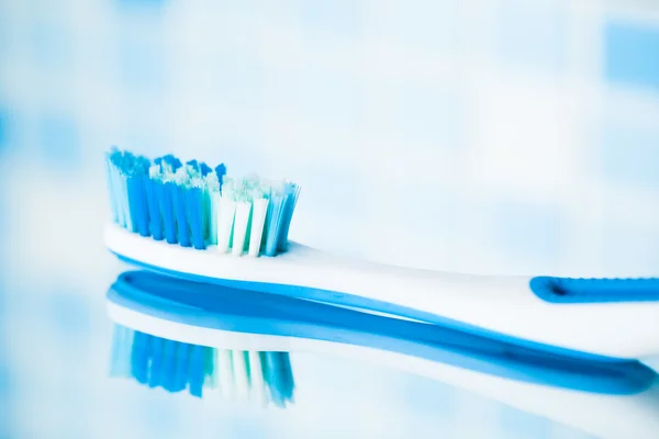 Tandborste på blå kakel bakgrund med spegelbild — Stockfoto