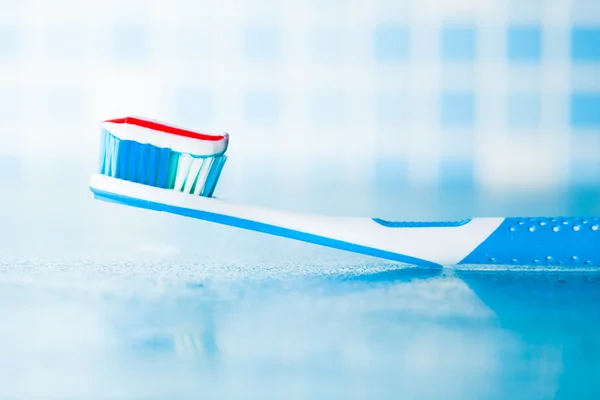 Escova de dentes com pasta de dentes listrada vermelha — Fotografia de Stock