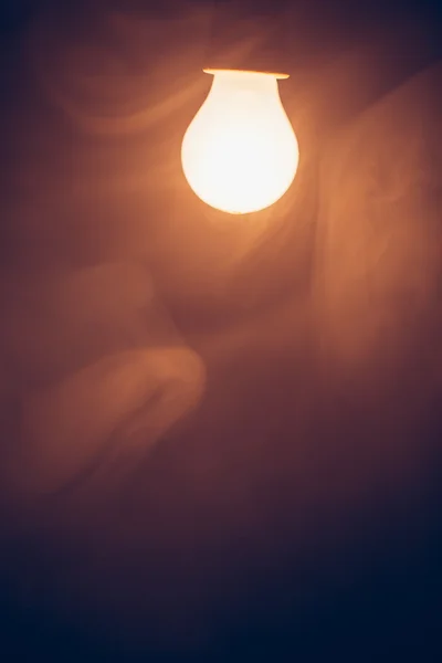 Lámpara de bombilla luz cálida en humo — Foto de Stock