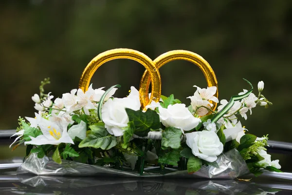 Anéis de casamento no carro com um monte de flores — Fotografia de Stock