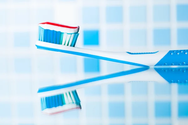 Escova de dentes com pasta de dentes listrada vermelha e reflexo do espelho — Fotografia de Stock