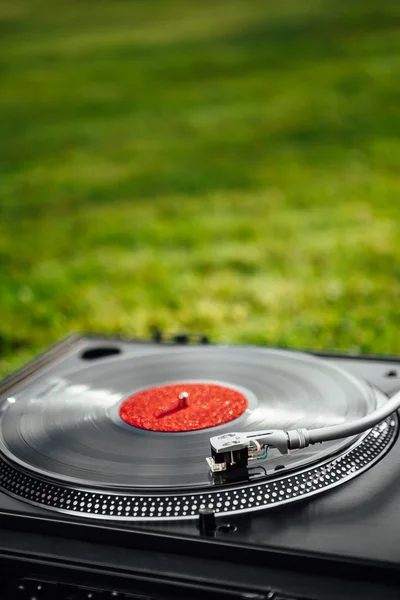 Turntable with LP vinyl record against green grass background — Stock Photo, Image