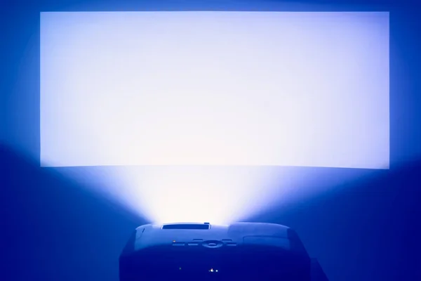 Проектор в дії з освітленим теплим синім екраном — стокове фото
