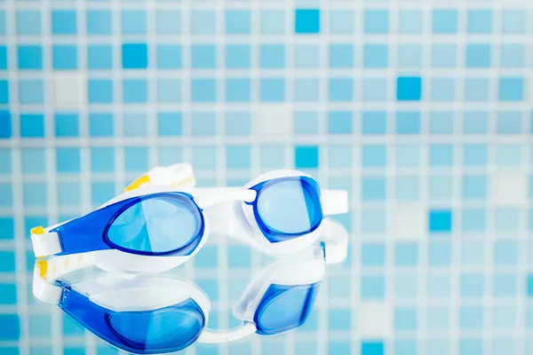 Professional swimming glasses for training or competition, blue tile background — Stock Photo, Image