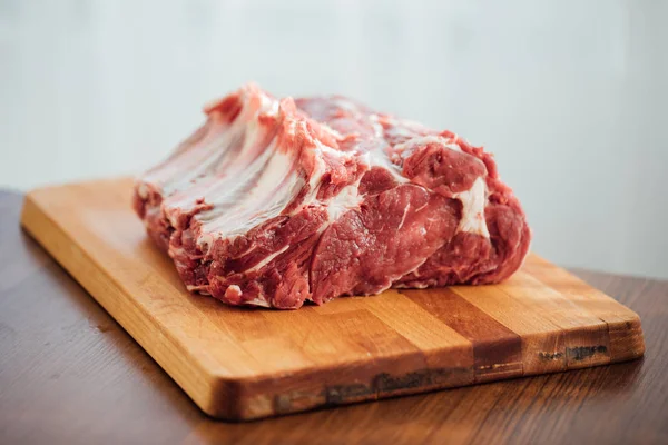 Pedaço de carne crua em tábua de madeira — Fotografia de Stock