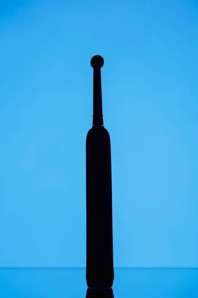 Электрический силуэт зубной щетки, синий фон — стоковое фото