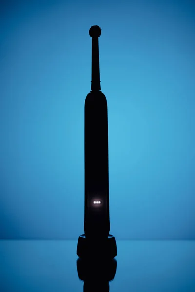 Spazzolino elettrico silhouette, sfondo blu — Foto Stock