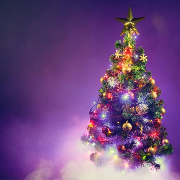 Kerstboom met feestelijke verlichting, paarse achtergrond met rook — Stockfoto