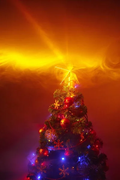Χριστουγεννιάτικο δέντρο με εορταστικά φώτα, πορτοκαλί φόντο με καπνό — Φωτογραφία Αρχείου