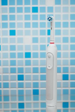 Mavi döşeme arka planı üzerinde elektrikli diş fırçası