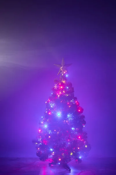 Árbol de Navidad con luces festivas en humo, fondo púrpura — Foto de Stock