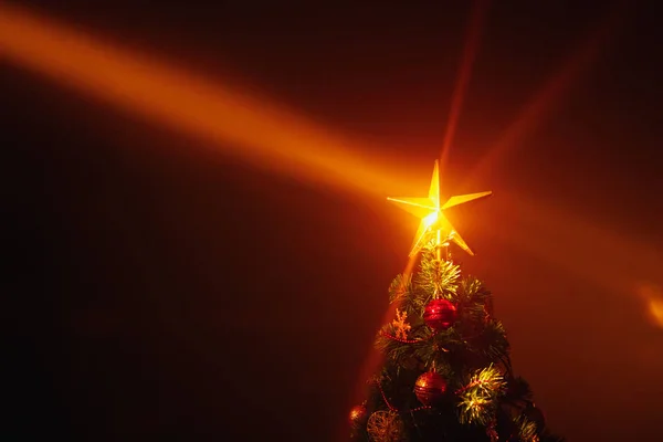 Kerstboom met feestelijke lichtjes, oranje achtergrond met mist — Stockfoto