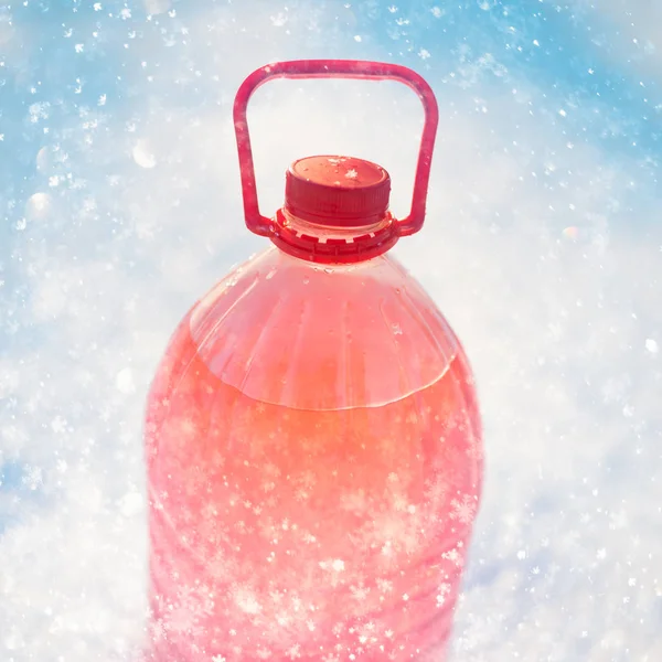 Fles met niet-bevriezing windscherm washer vloeibaar, sneeuwvlokken achtergrond — Stockfoto