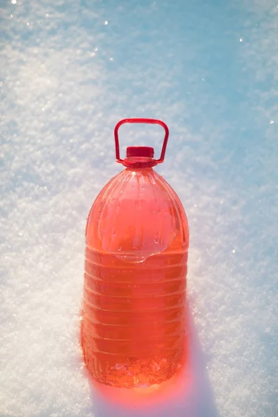 Fles met niet-bevriezing voorruit ruitensproeiervloeistof, sneeuw achtergrond — Stockfoto