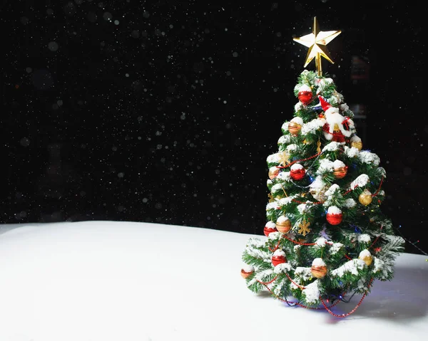 雪の中でお祝いの光とクリスマスツリー屋外、黒の夜の背景 — ストック写真