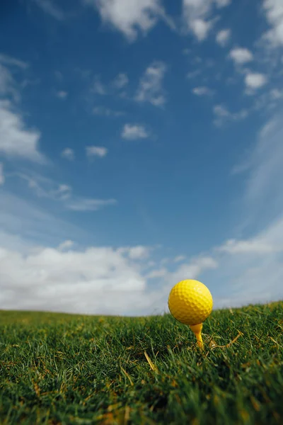 티, 녹색 잔디와 파란 하늘 배경에 노란색 골프공 — 스톡 사진