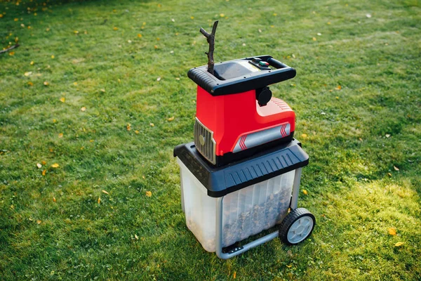 Astilladora de jardín, trituradora eléctrica (mulcher), fondo de hierba verde — Foto de Stock