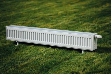 radiator on green lawn, ecological heating concept clipart