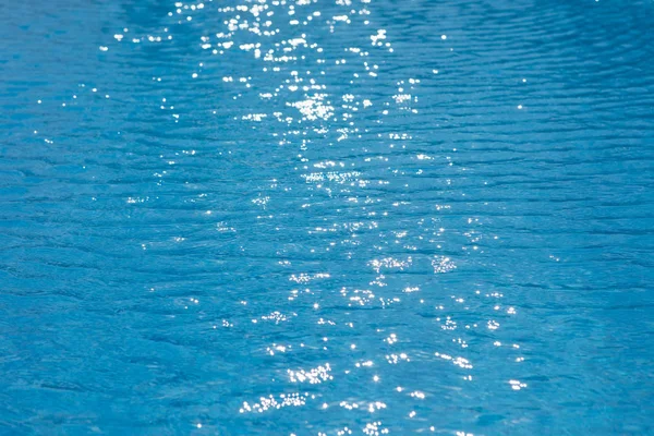 Doku güneşli parlama ile Yüzme havuzunda su ripples — Stok fotoğraf